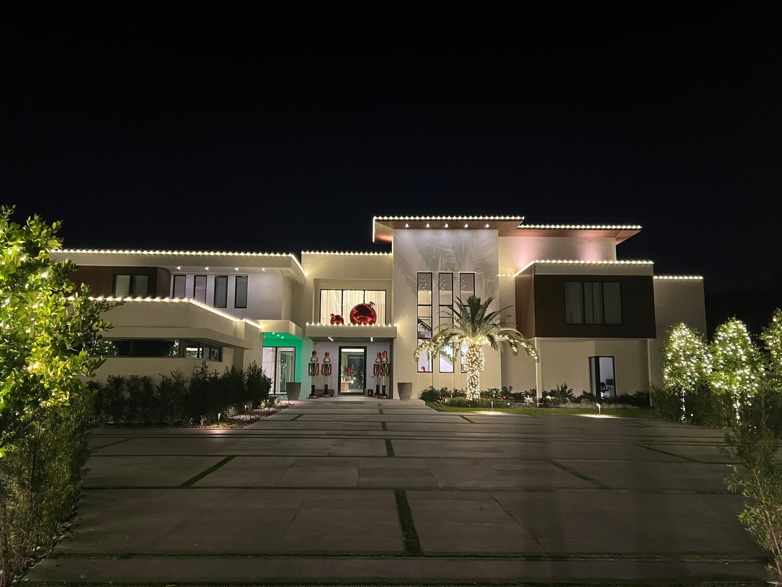 Gulfstream Glow nighttime install with a lit palm, oversized ornaments and nutcracker soldiers
